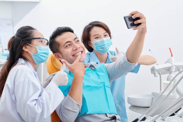 a patient taking a selfie with his dentist and dental assistant