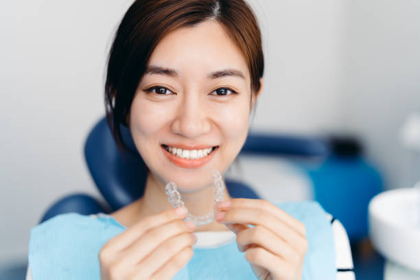 a satisfied woman smiling while holding her Invisalign