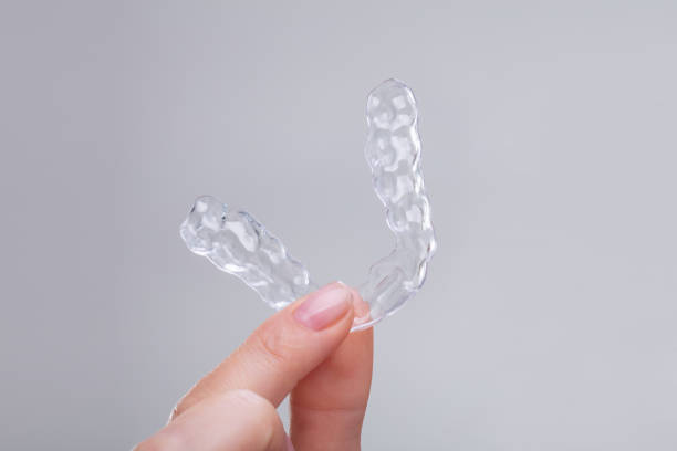 a person's hand holding Invisalign.