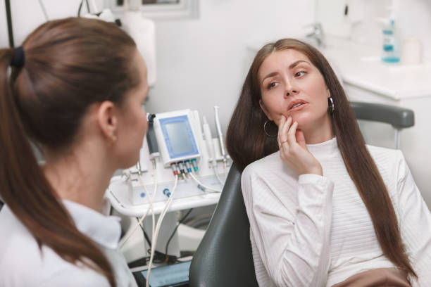 a woman looking in pain as she talks to her dentist while laying on the dental chair